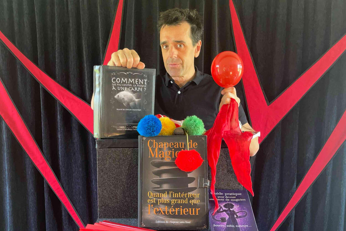 Spik Spakkk ! Monsieur Fred présente un livre magique et utilise une boîte pour faire apparaître des doudous sur scène, émerveillant les CCAS lors du spectacle